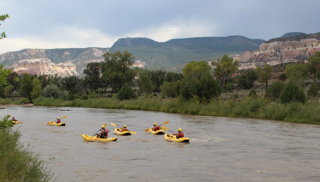 group of individuals in inflatable kayaks floating down the rio chama