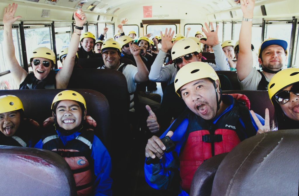 rafters wearing helmets and lifejackets on the shuttle bus heading to go white water rafting on the rio grande