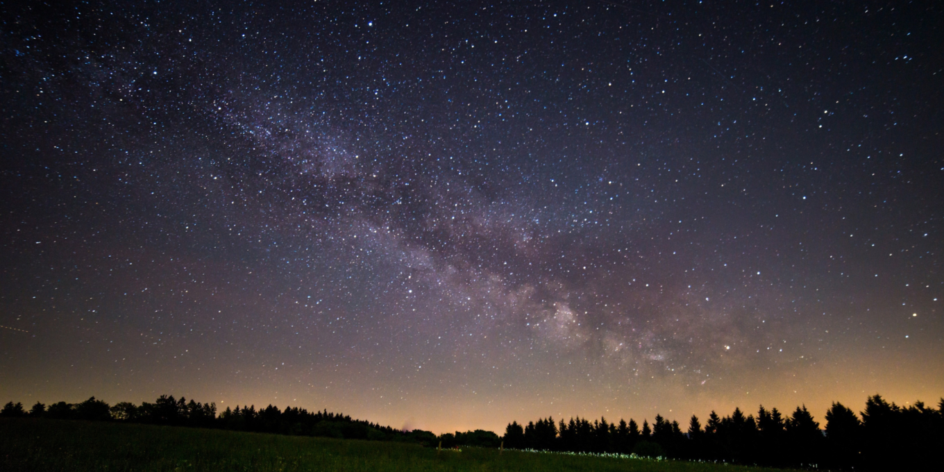 the night sky with stars and a purple and yellow hue