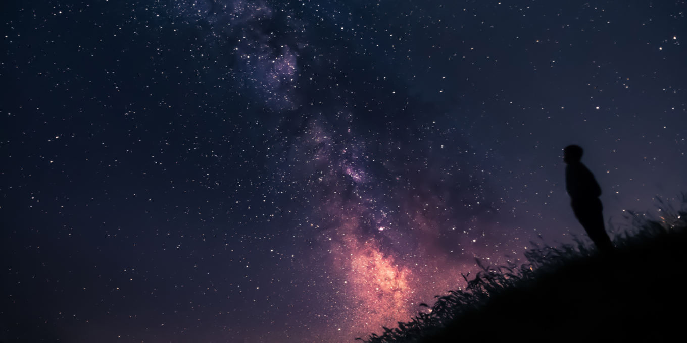 Person looking up at the pink and purple night sky